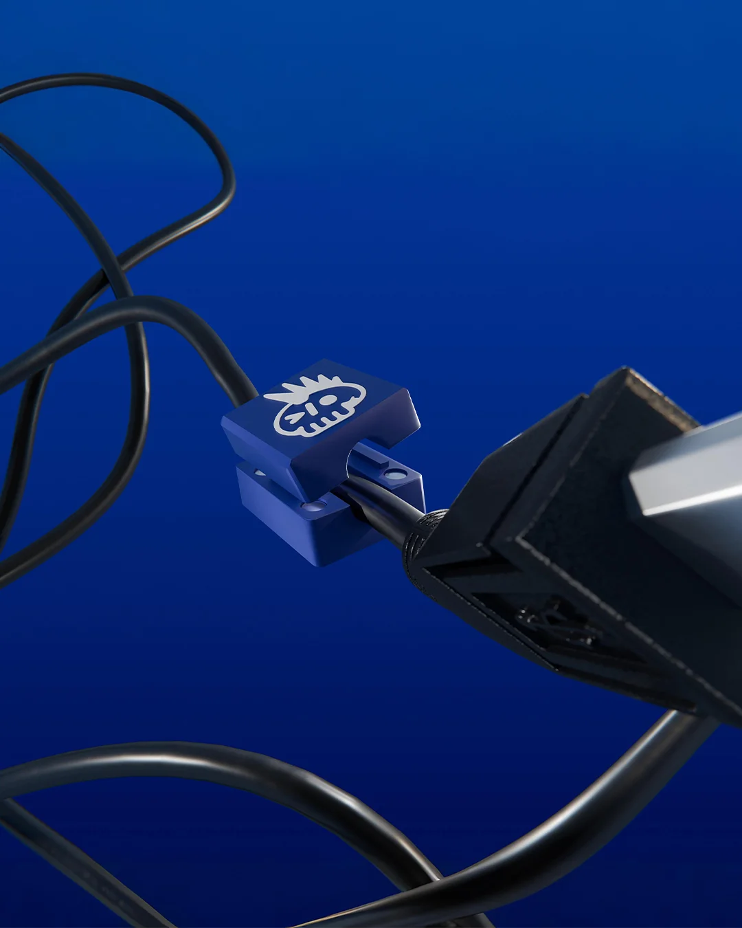 Devpunks - blue 3D-printed cable organiser with the punk skull, clipped onto a black cable, a Backdoor Studio project